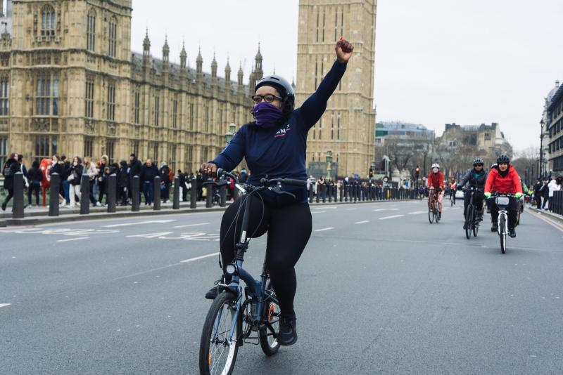 Woman with her arm raised in solidarity outside the Houses of Parliament, Westminster Bridge